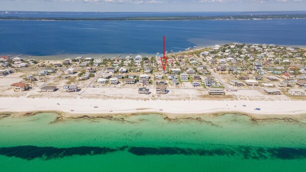 An aerial view of a coastal residential area with houses, a beach, and clear blue waters. - Nicely decorated home with private saltwater pool! Pet friendly! (Pensacola Beach)
