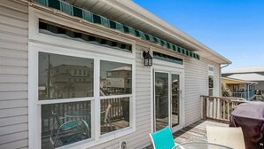 A covered outdoor deck with a glass table and chairs, a covered patio area, and a view of the neighborhood. - Nicely decorated home with private saltwater pool! Pet friendly! (Pensacola Beach)