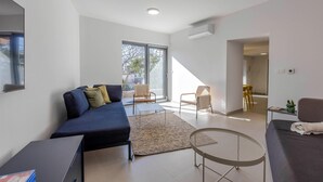 Ein modernes Wohnzimmer mit einem dunkelblauen Sofa, einem kleinen runden Tisch und einem großen Fenster, das für natürliches Licht sorgt.