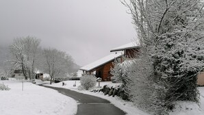 En snötäckt stig leder fram till en trästuga med ett snötäckt tak.
