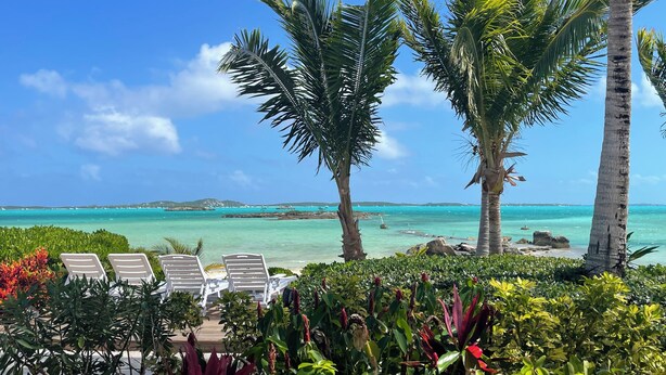 A beachside lounge with white lounge chairs and a view of the ocean. - Exuma Sol - Stunning Views from this Oceanfront Beach Cottage (George Town)