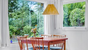 A dining area with a wooden table and chairs, a vase of flowers, and a window with a view of greenery. - 2 bedroom gorgeous home in Vig (Vig)