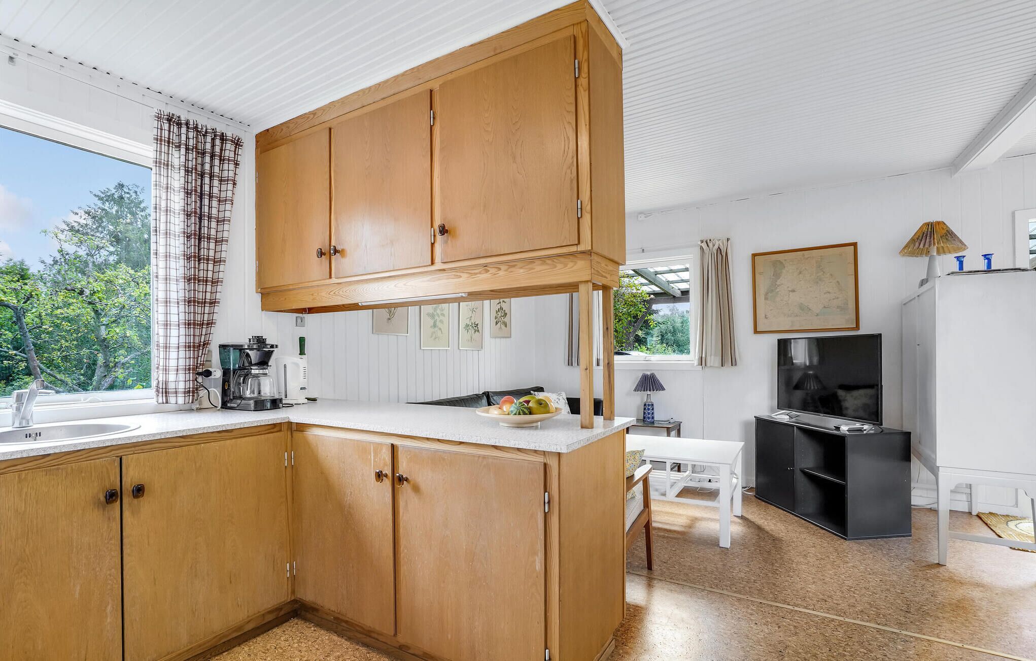 Una cocina con armarios de madera, un lavamanos y un comedor con mesa y sillas.