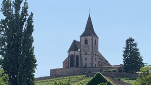 A historic church with a tall spire, surrounded by lush greenery and vineyards. - ALSACE COSY GITE 3 BEDROOMS 2 BATHROOMS (BUHL)