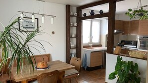 A kitchen with wooden cabinets, a sink, and a dining area with a table and chairs. - ALSACE COSY GITE 3 BEDROOMS 2 BATHROOMS (BUHL)