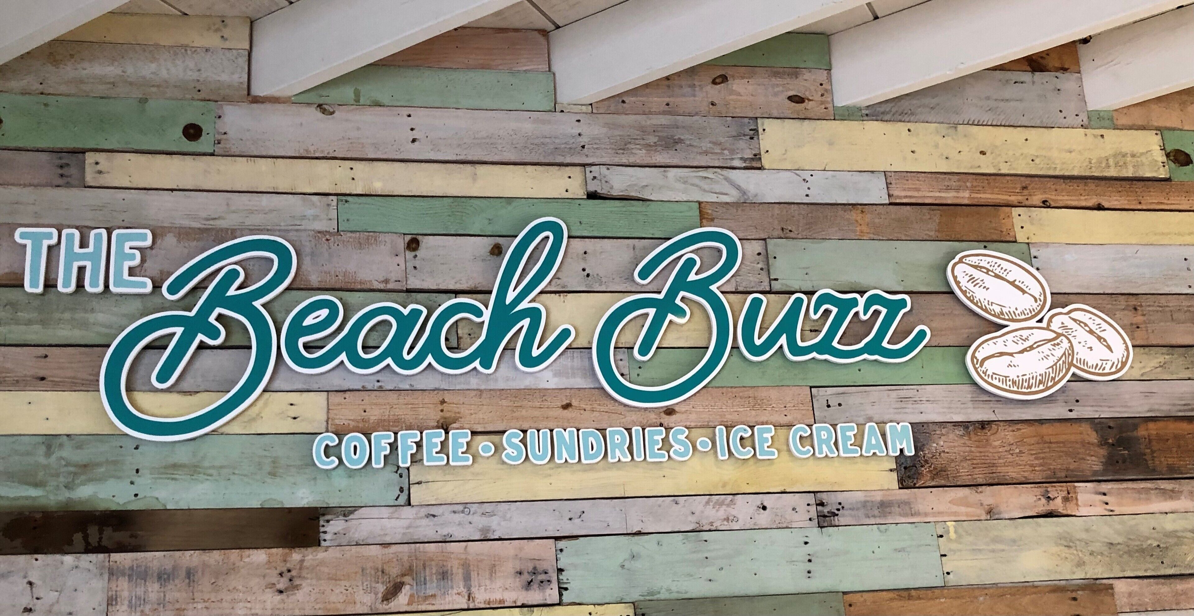 Opastekyltti, jossa lukee ”The Beach Brr”, ja jossa on logo sekä teksti, joka kertoo, että siellä on tarjolla kahvia, pientä purtavaa ja jäätelöä.