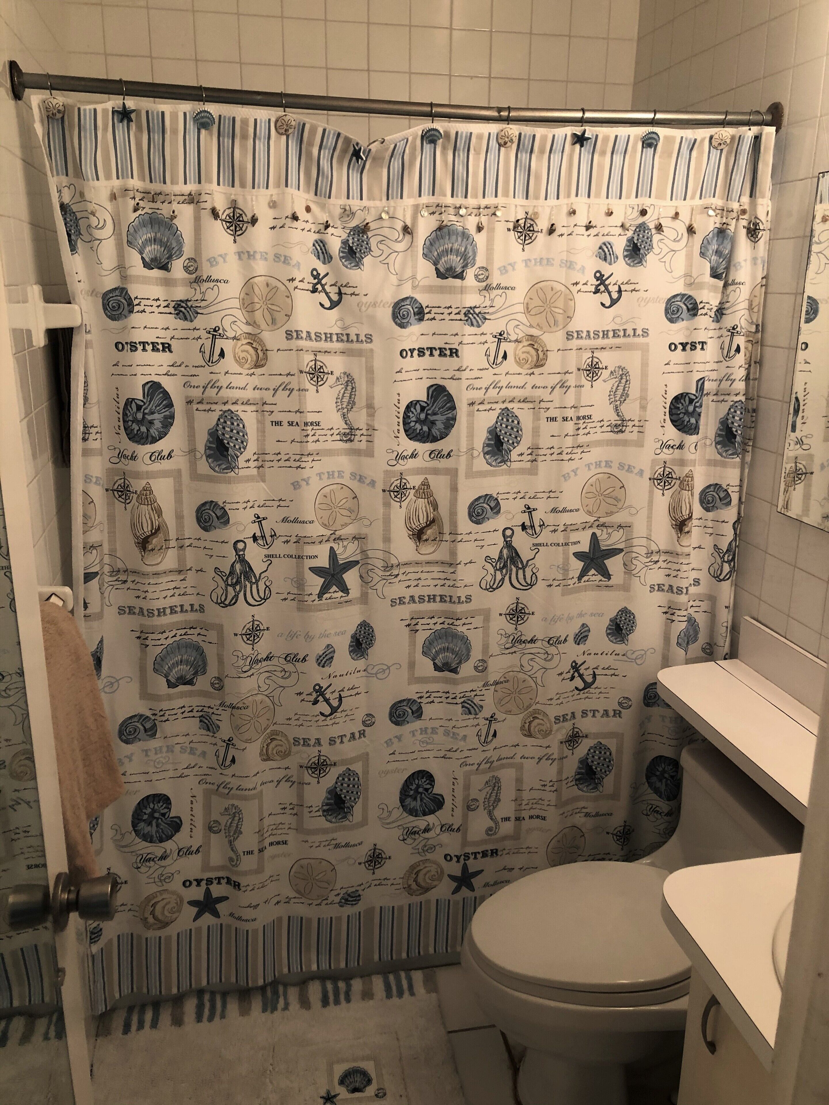 Ein Badezimmer mit einer Duschvorhang mit maritimer Dekoration, einer Toilette und einem Handtuchhalter.