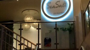 A staircase with a railing, a sign reading "SeaSalt St. Thomas", and a poster on the wall.