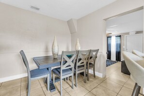 A dining area with a wooden table and chairs, a ceiling vent, and a door marked 'EXIT' in the background. - Spacious 5BR Getaway-Great for Families & Groups (Lauderdale Lakes)