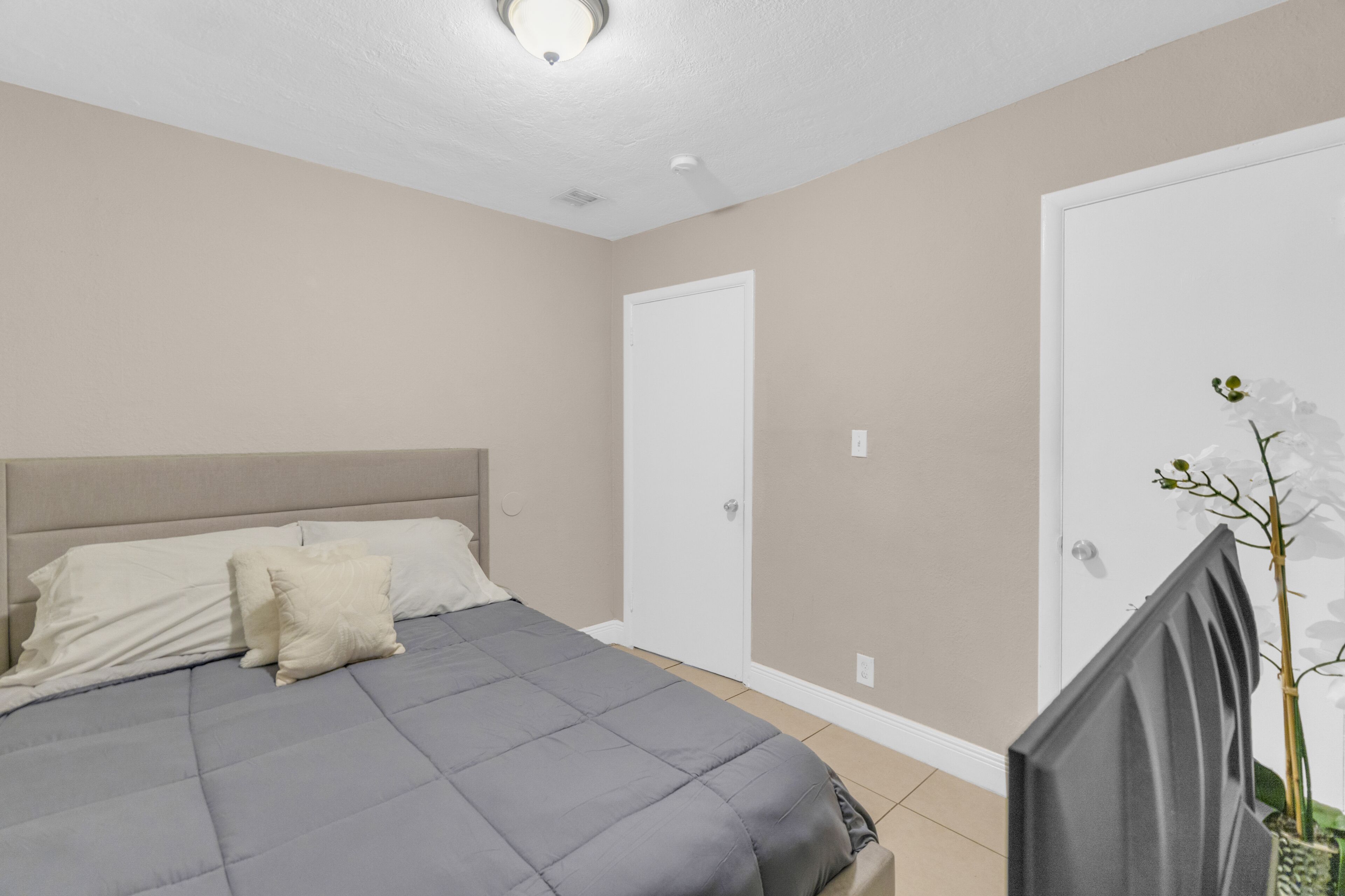 Un dormitorio con cama, mesita de noche, televisión y una puerta.