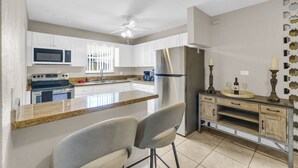 A kitchen with white cabinets, a stainless steel refrigerator, a microwave, a stove, and a ceiling fan. - Spacious 5BR Getaway-Great for Families & Groups (Lauderdale Lakes)