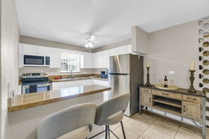 A kitchen with white cabinets, a stainless steel refrigerator, a microwave, a stove, and a ceiling fan. - Spacious 5BR Getaway-Great for Families & Groups (Lauderdale Lakes)