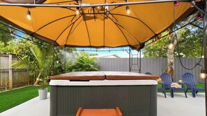 A hot tub with a canopy, surrounded by chairs and a small table. - Spacious 5BR Getaway-Great for Families & Groups (Lauderdale Lakes)