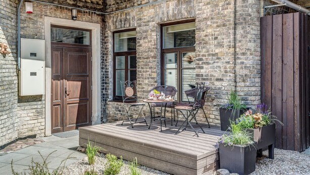 A brick building with a wooden deck, outdoor seating, and planters. - House of Nobles with personal terrace in Užupis (Vilnius)