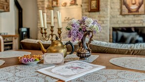 A cozy room with a wooden table, a brass teapot, a vase with flowers, and a welcome sign. - House of Nobles with personal terrace in Užupis (Vilnius)