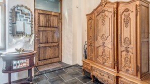 A wooden door with a glass panel, a wooden cabinet with intricate carvings, and a small table with a decorative bowl. - House of Nobles with personal terrace in Užupis (Vilnius)