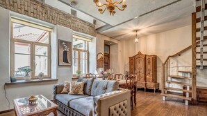 A cozy living room with a plush sofa, wooden furniture, and a staircase. - House of Nobles with personal terrace in Užupis (Vilnius)