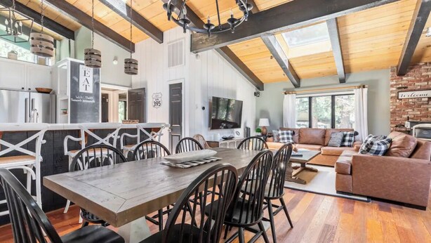 A spacious living area with a dining table, chairs, a sofa, and a TV.