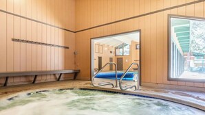 A hot tub area with wooden walls, a bench, and a view through a doorway.