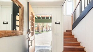 A wooden staircase leading to a door with a metal gate, a sign reading "KEYS" above it, and a view of a covered outdoor area with trees.