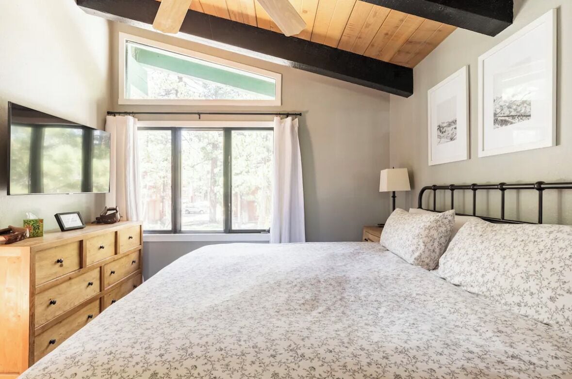 Une chambre avec un grand lit, une commode en bois et une fenêtre avec des rideaux.