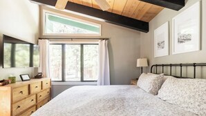 A bedroom with a large bed, wooden dresser, and a window with curtains.