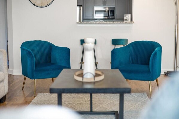 Een moderne woonkamer met twee teal fauteuils en een donkere salontafel met een decoratieve vaas.