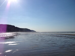 Ein Strand mit blauem Himmel und einer entfernten Klippe.