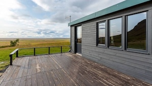 A modern building with large windows and a wooden deck. - Charming 2-bed Cottage Near Seljalandsfoss (Rangárþing eystra)