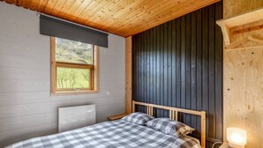 A bedroom with a bed, a window, and a bedside table with a lamp. - Charming 2-bed Cottage Near Seljalandsfoss (Rangárþing eystra)