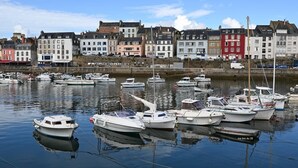 A marina with several boats docked, surrounded by historic buildings with varied architecture.