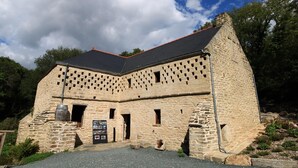 A stone building with a sloped roof and multiple windows.