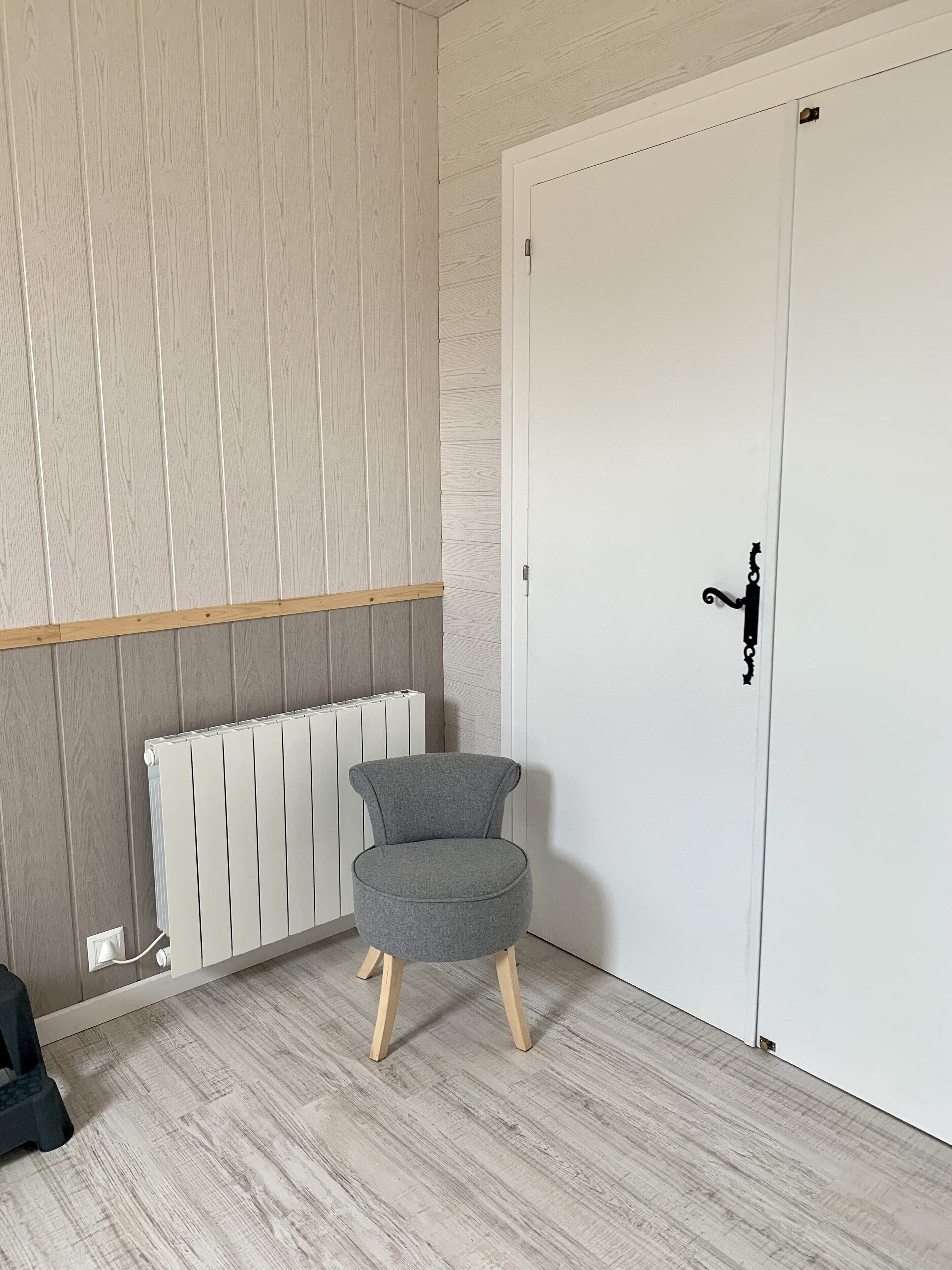 A room with a white door, a radiator, and a grey chair.