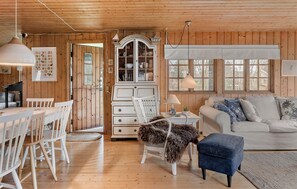 A cozy cabin interior with a dining area, a white cabinet, a sofa, and a lamp. - Awesome home in Askø with WiFi (Askø)