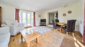 A living room with a sofa, a coffee table, a TV, and a dining area with a table and chairs.