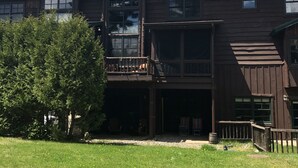 Een tweelaags houten gebouw met een balkon, een overdekte veranda en een gazon.