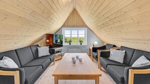 Una habitación acogedora con techo de madera, un ventanal con vistas, dos sofás, una mesa de centro y un televisor.