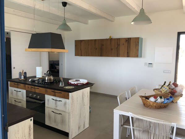 Una cucina moderna con isola centrale, mobili in legno e luci a sospensione.
