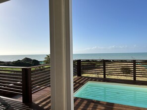 Un pontile in legno con piscina vetrata e vista sull'oceano.