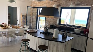 Een moderne keuken met een groot schiereiland, barstoelen en uitzicht op zee.