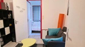 A compact living space with a sofa, a small yellow table, and a bookshelf. - ⭐✅ Studio privée-Rennes, 5mn de la gare-parking👍✅ (Rennes)