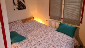 A bedroom with a bed, a radiator, a window with blinds, and a wall-mounted picture. - ⭐✅ Studio privée-Rennes, 5mn de la gare-parking👍✅ (Rennes)