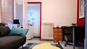 A compact living space with a sofa, a yellow round table, a radiator, a desk, and a plant. - ⭐✅ Studio privée-Rennes, 5mn de la gare-parking👍✅ (Rennes)