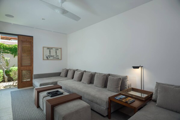 A modern living room with a grey sectional sofa, wooden coffee tables, and a floor lamp. - 5 Bedroom Luxury Villa at the Ritz Carlton Enclave (Los Cabos)