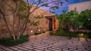 A paved pathway leading to a building with a stone facade and a modern entrance.