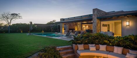 Un espacio exterior moderno con una chimenea, asientos al aire libre y una piscina.