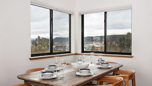 A dining area with a wooden table set for six, large windows with a view of the landscape, and a white wall. - Modern Apt w/ Mt Views & Grill Near Basalt & Aspen (Basalt)