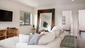 A modern bedroom with a large bed, a bench, a TV, and a large mirror. - Modern Apt w/ Mt Views & Grill Near Basalt & Aspen (Basalt)
