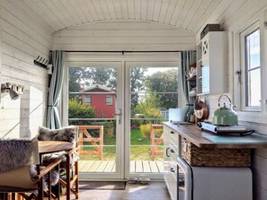 Eine gemütliche Küche mit einer Schiebetür zu einer Holzterrasse und einem roten Haus im Hintergrund.