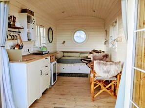 Ein kompakter Raum im Chalet-Stil mit Küchenzeile, einem Rundfenster und einer gemütlichen Sitzecke mit Felldecke.